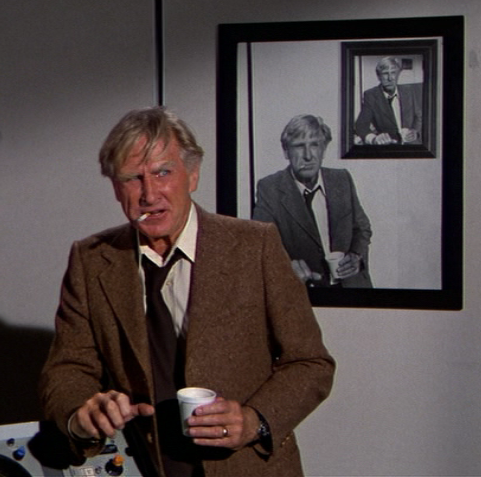 Lloyd Bridges in movie 'Airplane!',with cup of coffee and cigarette, in front of photos showing him in exactly the same pose.