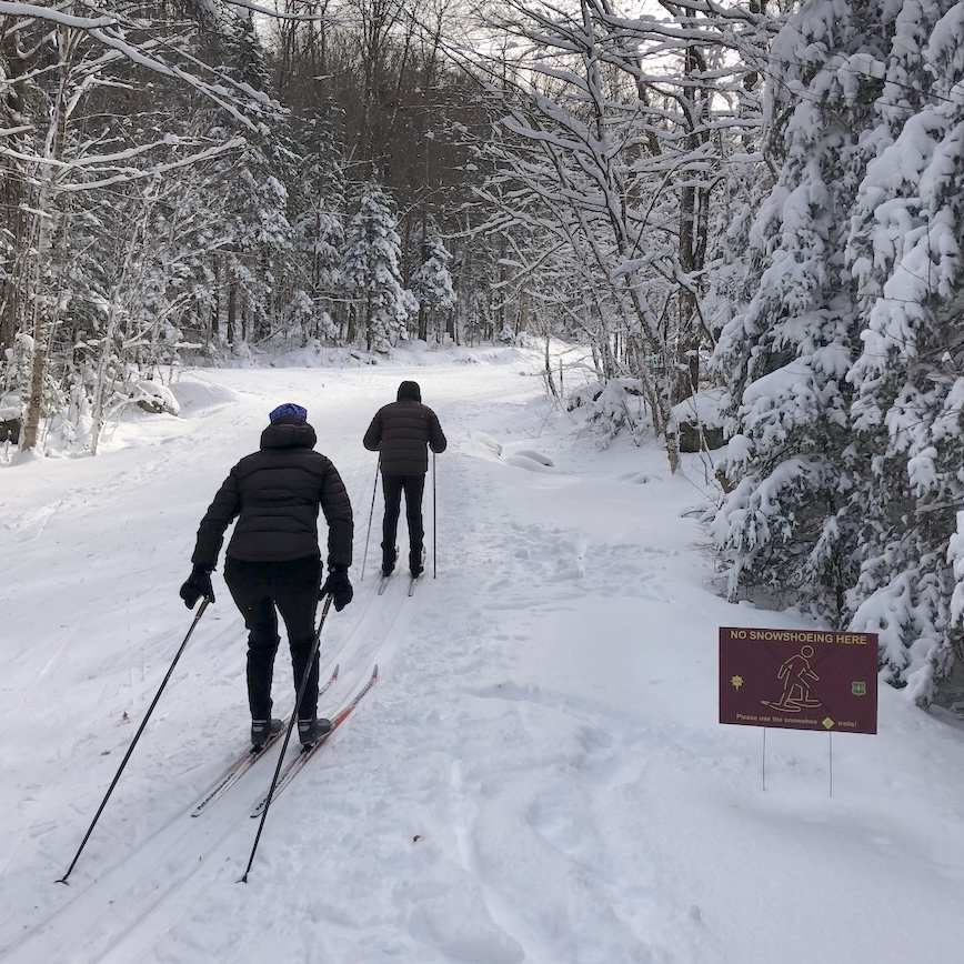 Cross country skiers at Prospect Mountain double-poling by a sign marked 'No Snowshoeing Here'