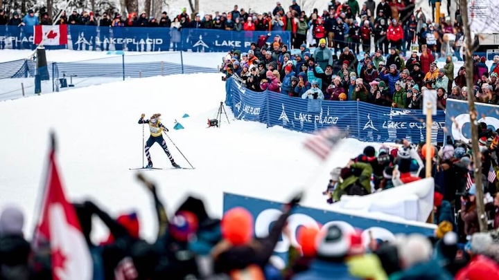 Jessie Diggins skiing at Mt. van Hoevenber, watched by a large crowd of spectators.
